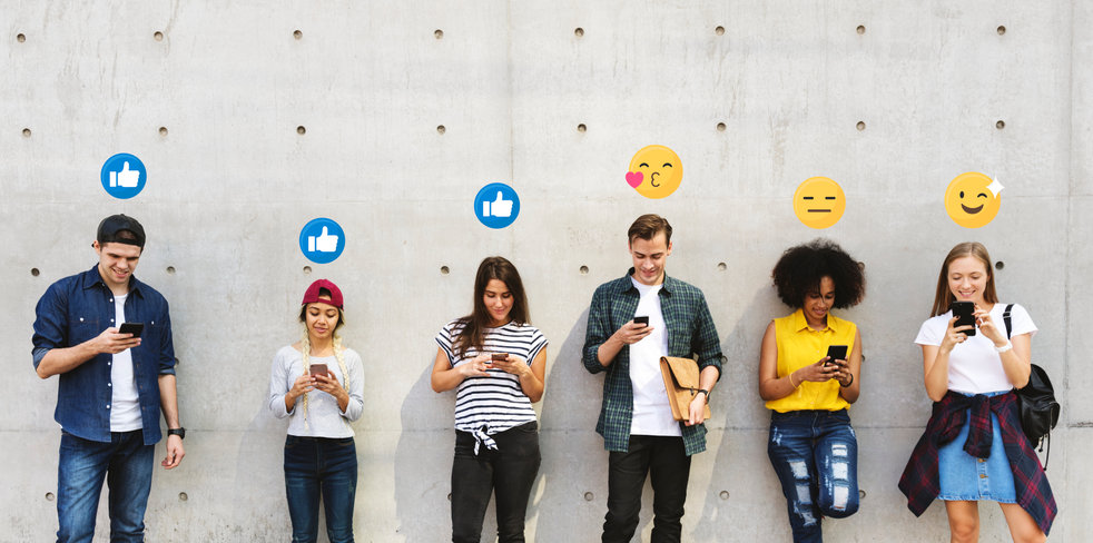 Teenagers consume media on their cellphones with emoticons showing their emotions.