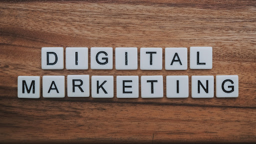 Scrabble tiles on a wooden background spell out “DIGITAL MARKETING”.