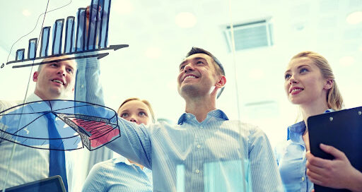 Smiling business team drawing chart on notice board in office.