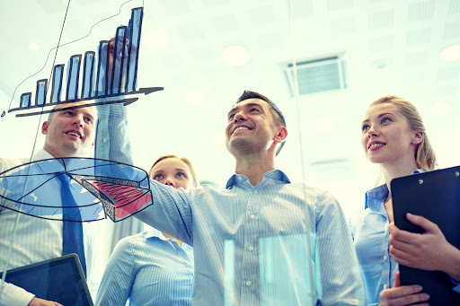 Smiling business team drawing chart on notice board in office.