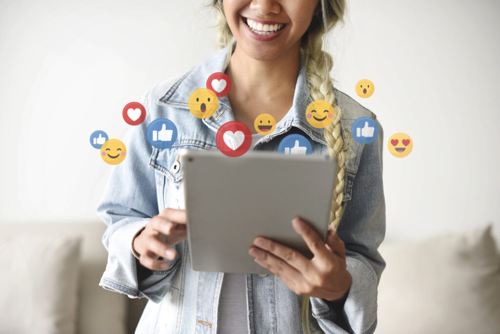 A woman holds a tablet displaying various social media icons.