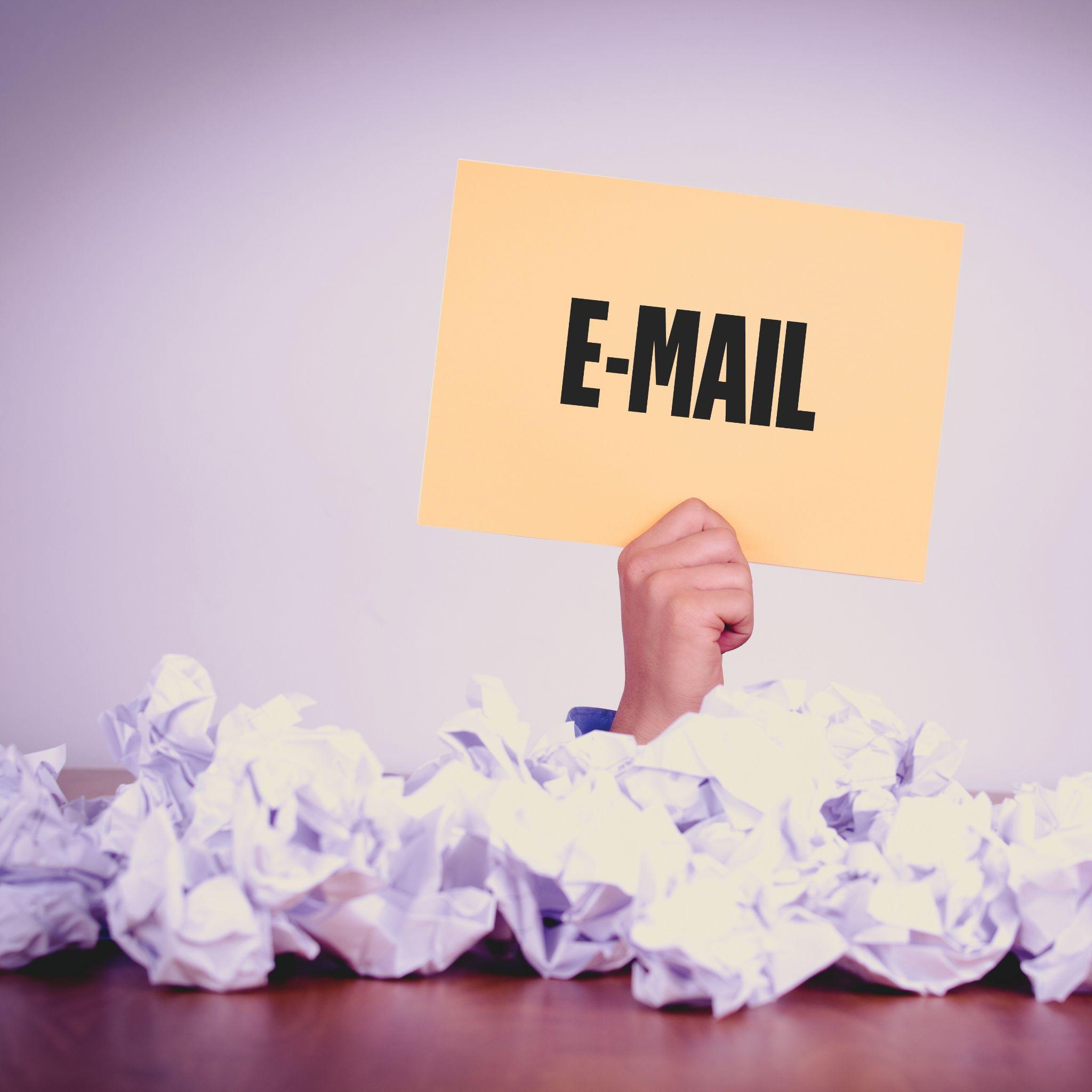 A hand holds an 'Email' paper amidst crumpled papers, symbolizing personalized email mark