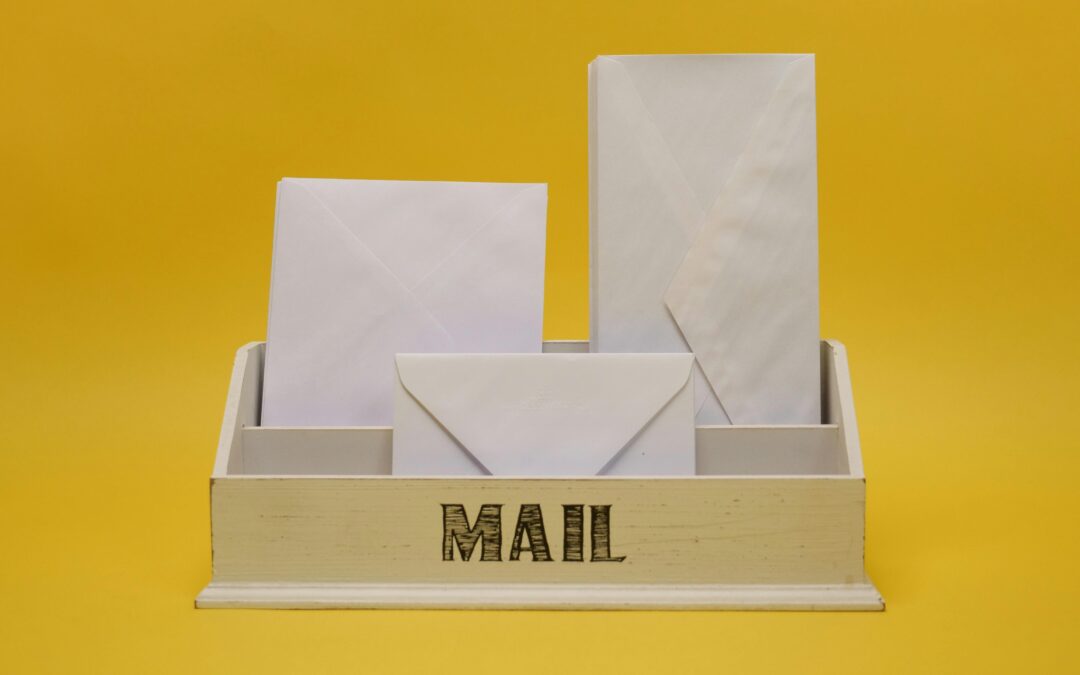 White envelopes are arranged in a wooden organizer with MAIL written on it.