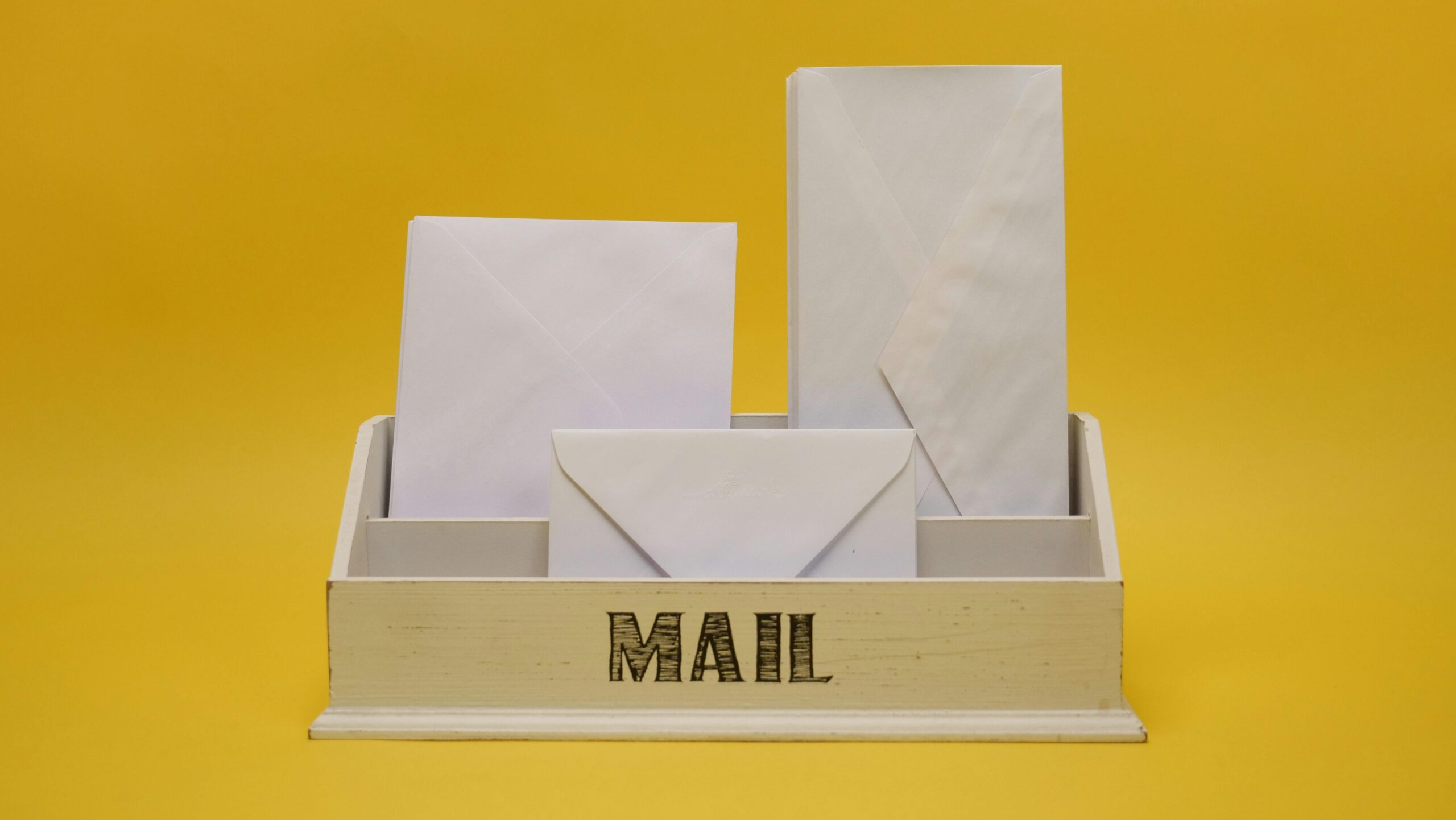 White envelopes are arranged in a wooden organizer with MAIL written on it Direct mail marketing