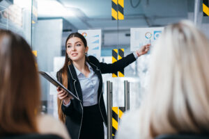 A sales trainer presents performance charts to a small team during a business meeting, illustrating sales team training, coaching, and strategies for improving closing skills and sales performance.