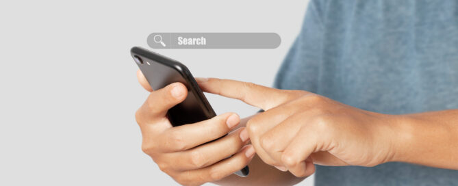Close-up of a person using a smartphone to search online, representing how customers look for local businesses and services before making a purchasing decision.
