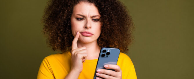 Confused woman checking her phone for inconsistent business contact information